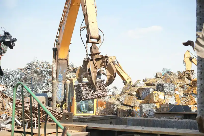 Kepçeli iş makinesi hurda metal yığını üzerinde çalışıyor