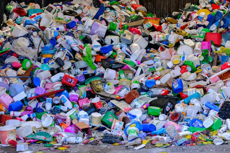 Geri dönüşüm tesisinde yığılmış renkli sert plastik kap ve bidonlar